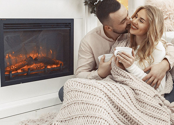Couple cozy by fireplace maintained by Ricks Affordable Heating and Cooling in Perrysburg, Ohio