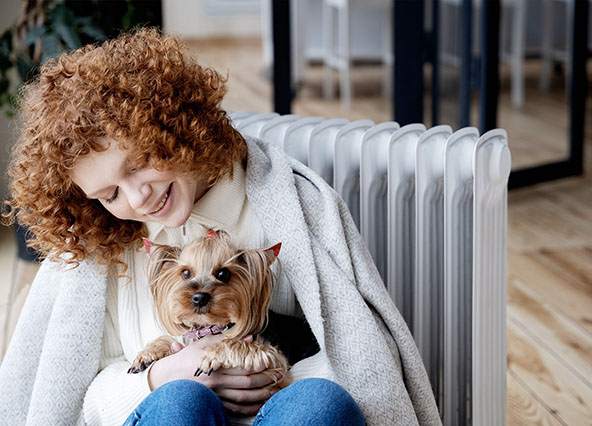 Woman and dog sitting cozy in warm home after having heat pump maintenanced by Ricks Affordable Heating & Cooling