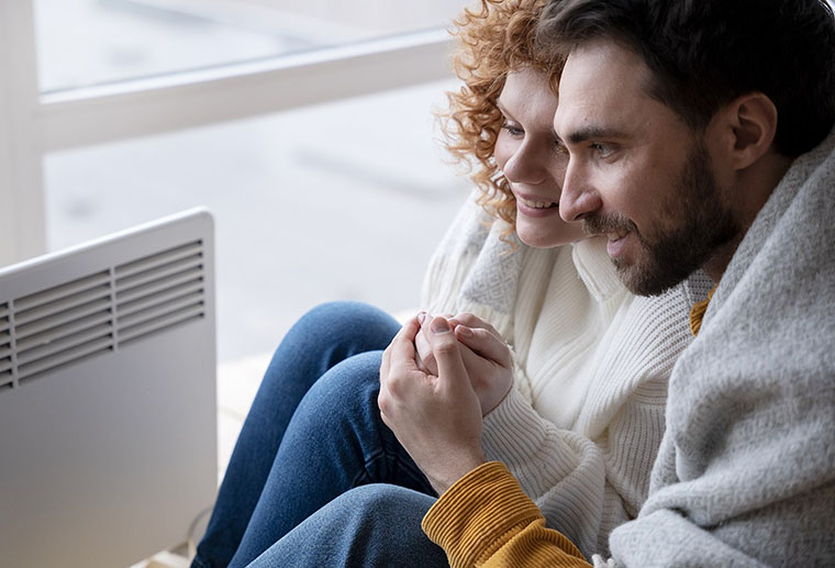 Couple sitting cozy in warm home after having heat pump maintenanced by Ricks Affordable Heating & Cooling