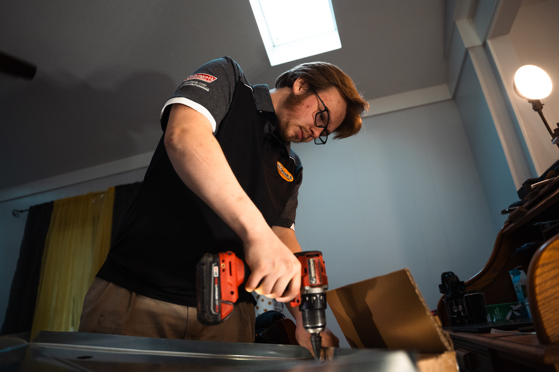 Rick's Affordable technician using a drill during an HVAC installation