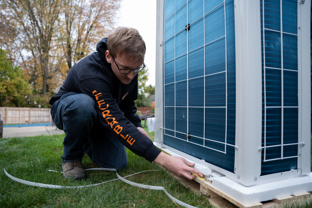 Rick's Affordable technician measuring and leveling a new outdoor AC unit during installation